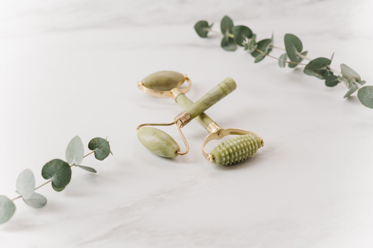 Chic jade rollers styled with eucalyptus leaves on a marble surface, perfect for self-care focuses.