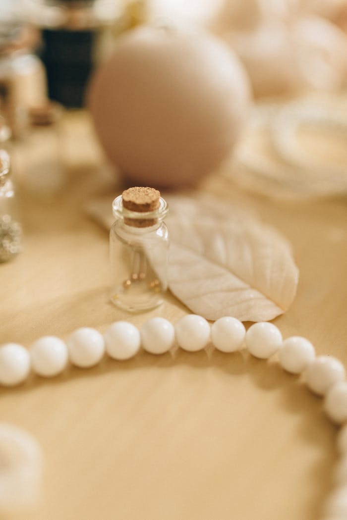 Close-up of white beads and small glass bottles on a warm-toned surface, depicting elegance and luxury.