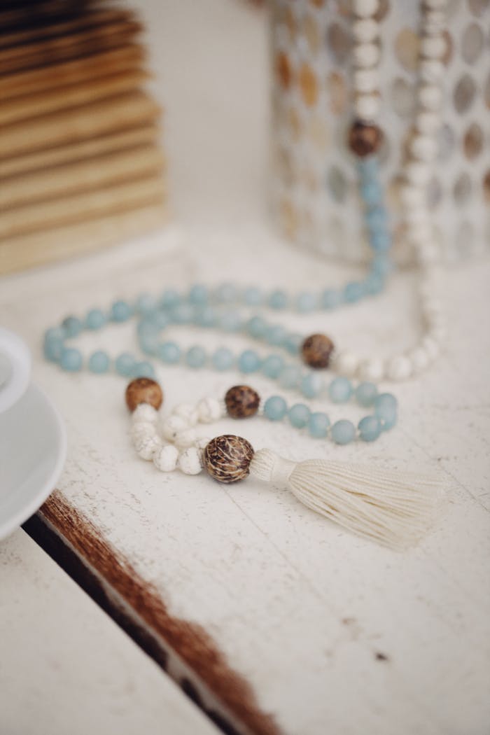 A decorative beaded necklace with a tassel elegantly arranged on a rustic wooden table.